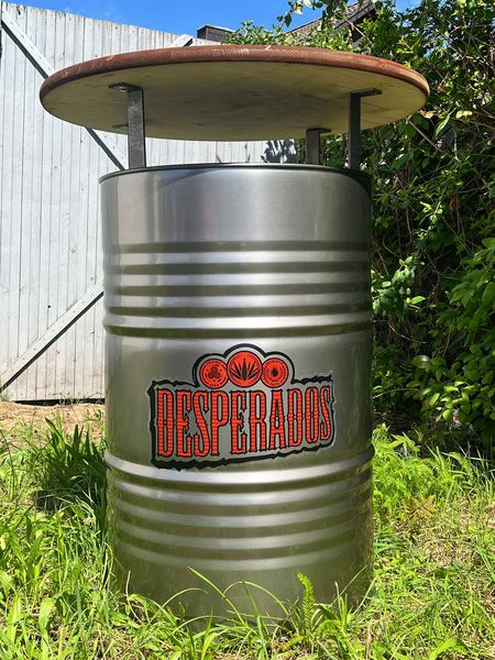 Der Desperados-Fasstisch ist ein robuster Stehtisch aus recyceltem Ölfass mit hochwertiger Douglasien-Holzplatte, ideal für Bars, Beachclubs und Terrassen. Der individuell gebrandete Fass-Stehtisch kombiniert industrielles Design mit sommerlichem Flair und sorgt für ein einzigartiges Gästeerlebnis im Außenbereich.