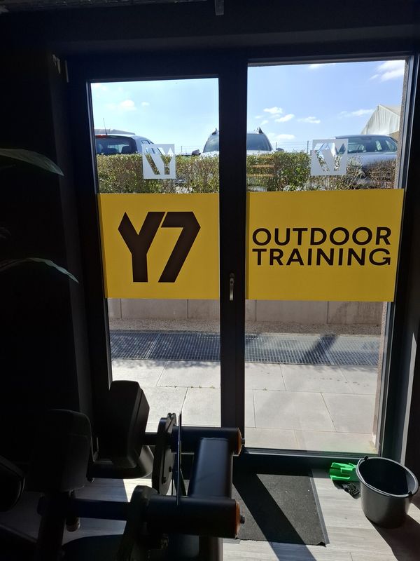 Die Fensterbeschriftung für das Y7 GYM ist mit gelber Folienkaschierung im Innenraum auf die Glasflächen montiert und ist durch die hohe Deckkraft perfekt für die Außenfront lesbar. Eine ideale Werbung, um auf das Outdoor-Training aufmerksam zu machen und gleichzeitig als Sichtschutz zu dienen.