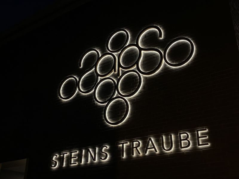 Diese Rückbeleuchtung mit LED-Technik schafft Tiefe, wirkt hochwertig und zieht die Aufmerksamkeit der Gäste gezielt auf das Firmenlogo. Besonders in der Gastronomie, in Vinotheken oder Weingütern ist eine individuell gestaltete Leuchtreklame ein entscheidender Faktor für Wiedererkennung und Ambiente.